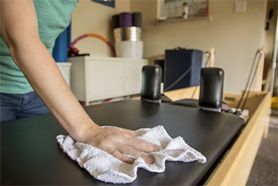 Wiping down a Pilates Reformer machine at Wilder Pilates in Lenexa Kansas